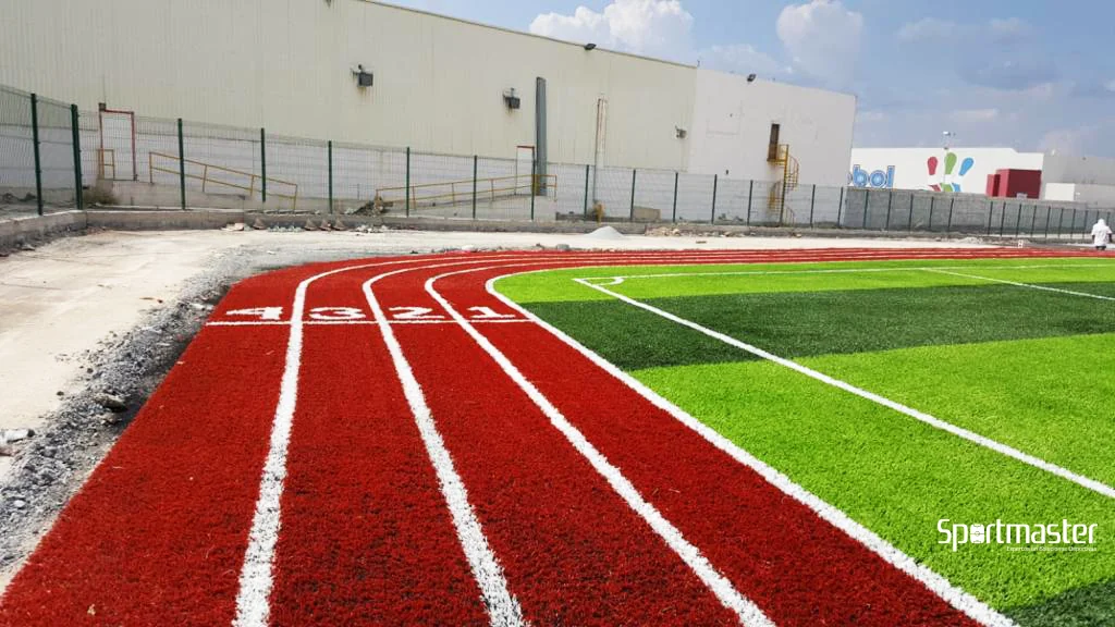 pista de atletismo sintética de pasto sintético color terracota junto a cancha de fútbol — instalación Sportmaster